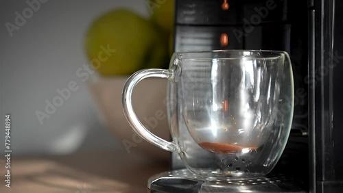 Hot morning espresso coffee pouring from the coffee machine into transparent cup. 
