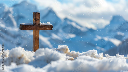 Small wooden Christian cross in middle of snow and snowy mountains in background and copy space