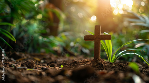 Small wooden Christian cross in the ground and lush nature forest in background and copy space photo
