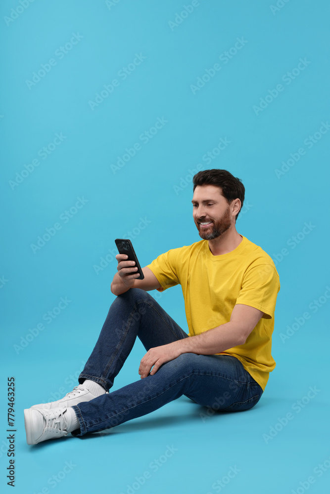 Smiling man with smartphone on light blue background Smiling man with smartphone on light blue background