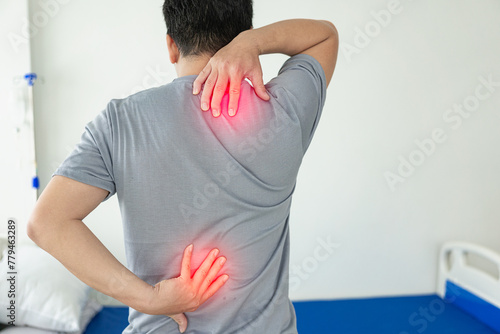 Young man with back pain touching his lower back and neck Waking up with muscle stiffness Copy space