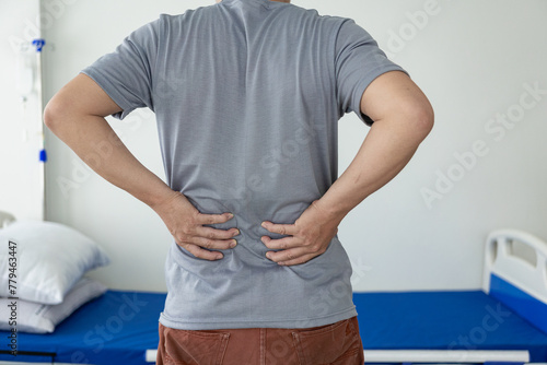 Young man with back pain touching his lower back and neck Waking up with muscle stiffness Copy space