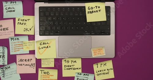 Top view on office desk with laptop computer and post it notes all around. Overwhelmed with work concept.