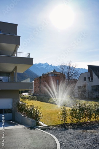 Dramatic sprinkler watering yards in the winter sun in Vaduz, Liechtenstein
