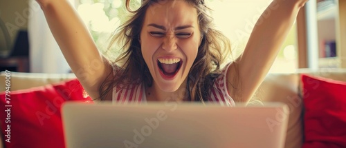 An overjoyed woman celebrates a victorious moment while working on her laptop photo