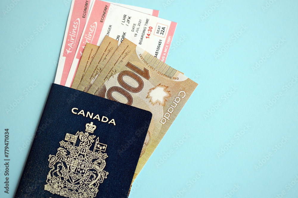 Fototapeta premium Canadian passport with money and airline tickets on blue background close up. Tourism and travel concept