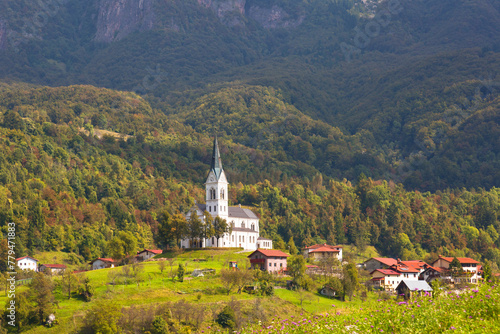 A small village with a church on a background of mountains, Alps