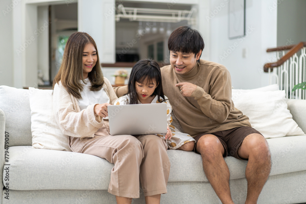 Father and mother with asian kid girl learn on laptop computer reviewing lesson study with online education e-learning.student look for educational knowledge in homeschool at home.Education - obrazy, fototapety, plakaty 