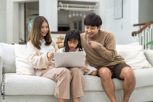 Father and mother with asian kid girl learn on laptop computer reviewing lesson study with online education e-learning.student look for educational knowledge in homeschool at home.Education