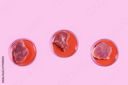 Three Petri dishes with lab-grown artificial meat on pink background