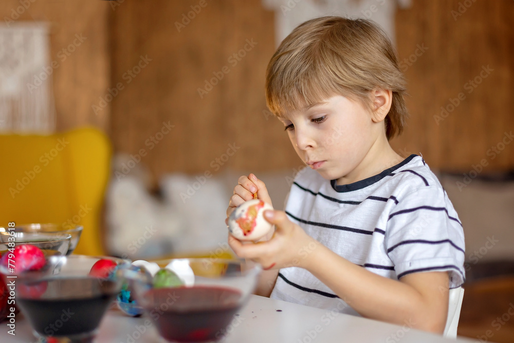 Beatiful blond child, boy, coloring and painting eggs for Easter at home Beatiful blond child, boy, coloring and painting eggs for Easter at home