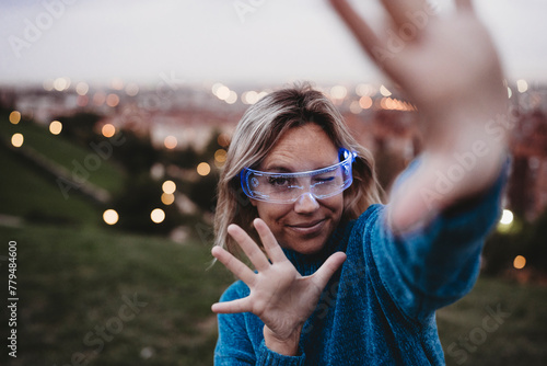 Playful woman wearing smart glasses and gesturing at dusk photo