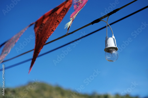 Equipped and electrical with light bulbs is hanging in the wind and sunlight on blue sky
