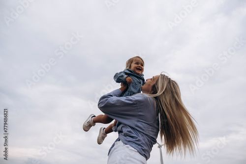 Happy woman holding daughter aloft under sky photo