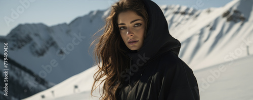 Beautiful young woman in black hoodie in mountains. Amazing snowy mountains, winter landscape