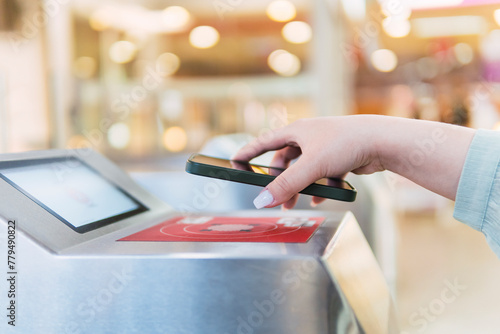 Hand of woman scanning QR code through smart phone at turnstile