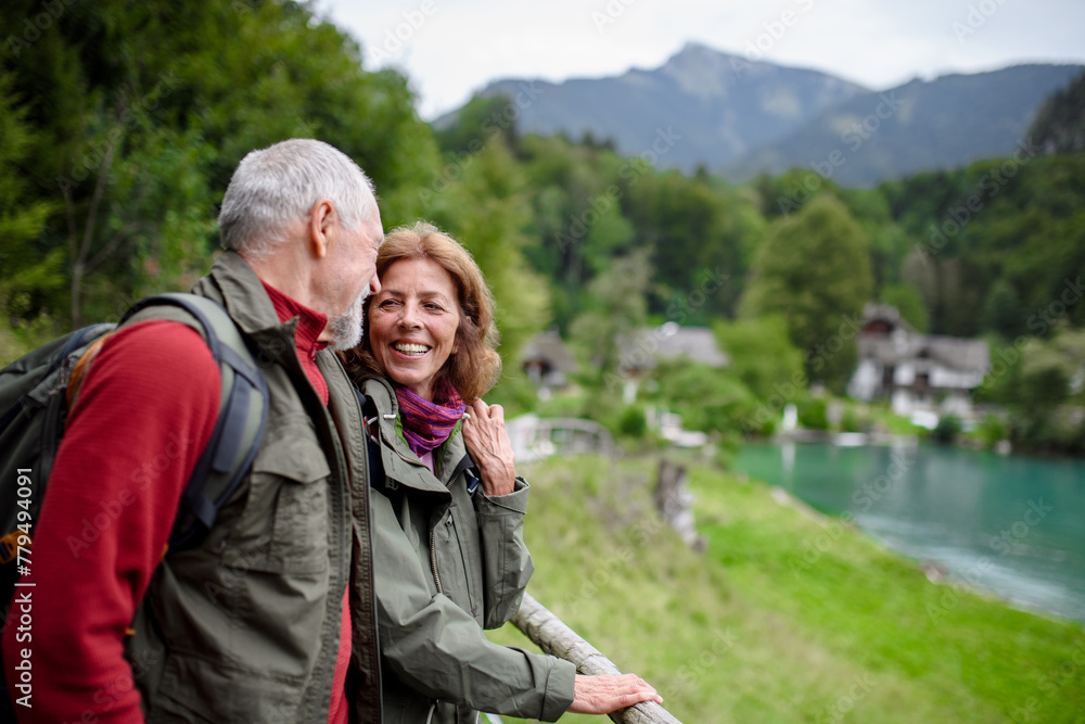Active elderly couple hiking together in autumn mountains. Senior tourists enjoying view on lake