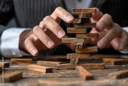 A man is holding a stack of wooden blocks and is about to topple them photo