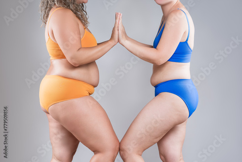 Two overweight women with cellulitis, fat flabby bellies, legs, hands, hips and buttocks on gray background, obese female body, liposuction and plastic surgery concept photo