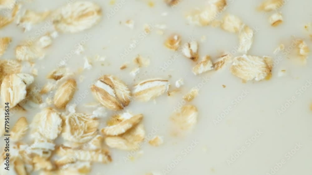 Oat flakes pouring into oat plant-based milk, slow motion. Oat flakes pouring into oat plant-based milk, slow motion.