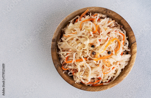 Sauerkraut with carrots and pepper in wooden bowl. Top view.