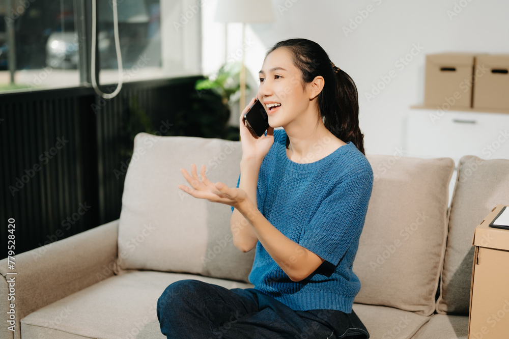 Asian Business woman Talking on the phone and using a laptop with a smile while sitting on sofa Asian Business woman Talking on the phone and using a laptop with a smile while sitting on sofa