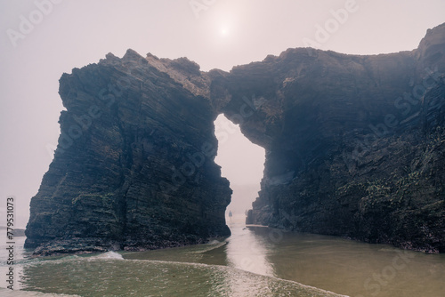 Cathedrals beach in Galicia, Spainn. Foggy landscape with Playa de Las Catedrales Catedrais beach in Ribadeo, Lugo on Santabrian coast. Natural archs of Cathedrals beach. Moody rock formations photo