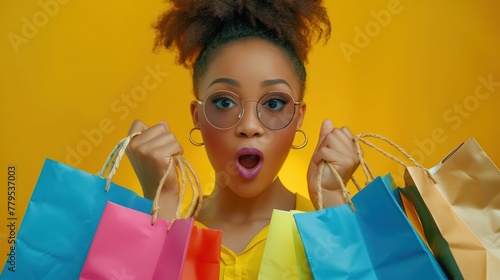 Stylish chic African American woman with colorful shopping bags in surprise sale concept isolated on yellow banner background.