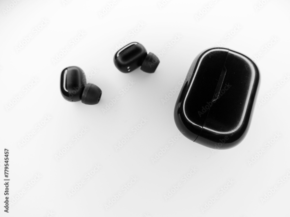 Top view grayscale of wireless earbuds and a plastic powerbank on a white background Top view grayscale of wireless earbuds and a plastic powerbank on a white background
