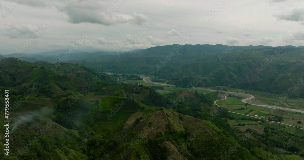 Mountain province with green hills and forest. Farm fields over the agricultural land near the river. Mindanao, Philippines. Mountain province with green hills and forest. Farm fields over the agricultural land near the river. Mindanao, Philippines.