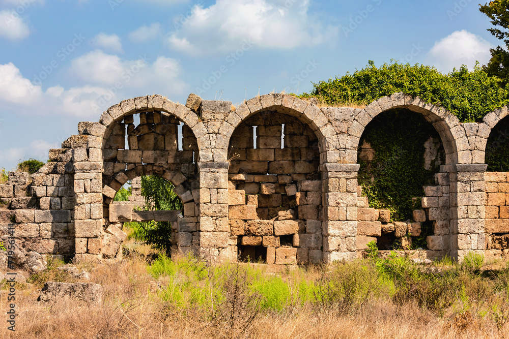 Sunlit arches of defensive wall of Perge against a blue sky. Aksu, Antalya, Turkey (Turkiye)