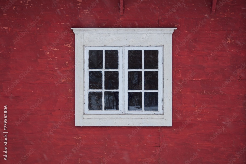 Closeup of a white framed window on red wooden wall.