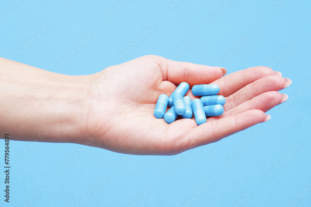 Medicine background. Blue pills isolated on blue. Pile of capsules. Tablets background. Vibrant vivid color drugs. Antibiotics background. Holding blue pills. Drugs on hand. Diet supplementation. Medicine background. Blue pills isolated on blue. Pile of capsules. Tablets background. Vibrant vivid color drugs. Antibiotics background. Holding blue pills. Drugs on hand. Diet supplementation.