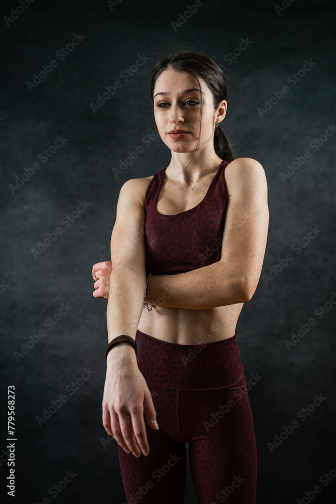 Young slim female fitness trainer wearing sports bra posign at studio isolated on black Young slim female fitness trainer wearing sports bra posign at studio isolated on black