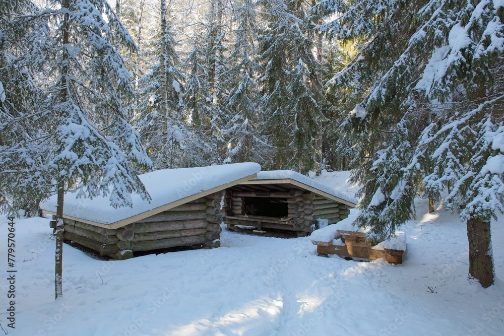 Traditional wooden leanto shelter with fireplace in forest with snow on the ground in winter, Räyskälä, Finland. Traditional wooden leanto shelter with fireplace in forest with snow on the ground in winter, Räyskälä, Finland.
