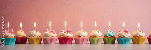 Colorful cupcakes with lit candles are displayed against a pink background, indicating an indoor celebration event marking of joy and celebrating. with free space