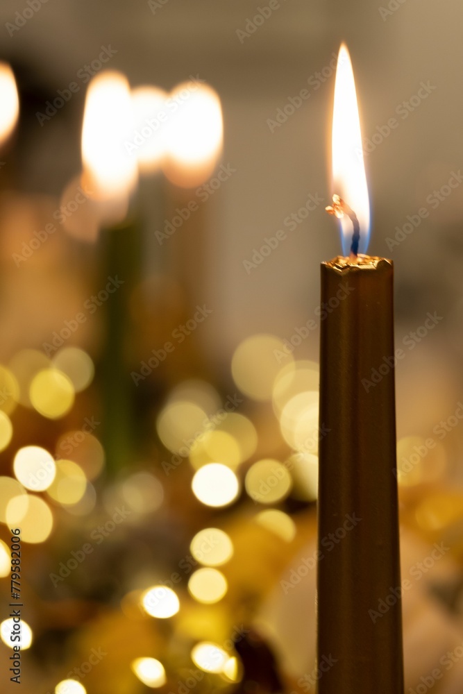 Vertical shot of a lit candle with bokeh lights in the blurred background for Thanksgiving dinner Vertical shot of a lit candle with bokeh lights in the blurred background for Thanksgiving dinner