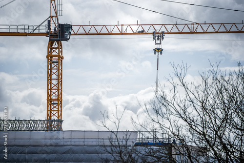 Construction crane above flame retardant scaffold sheeting wrapped apartments building during insulation in england uk