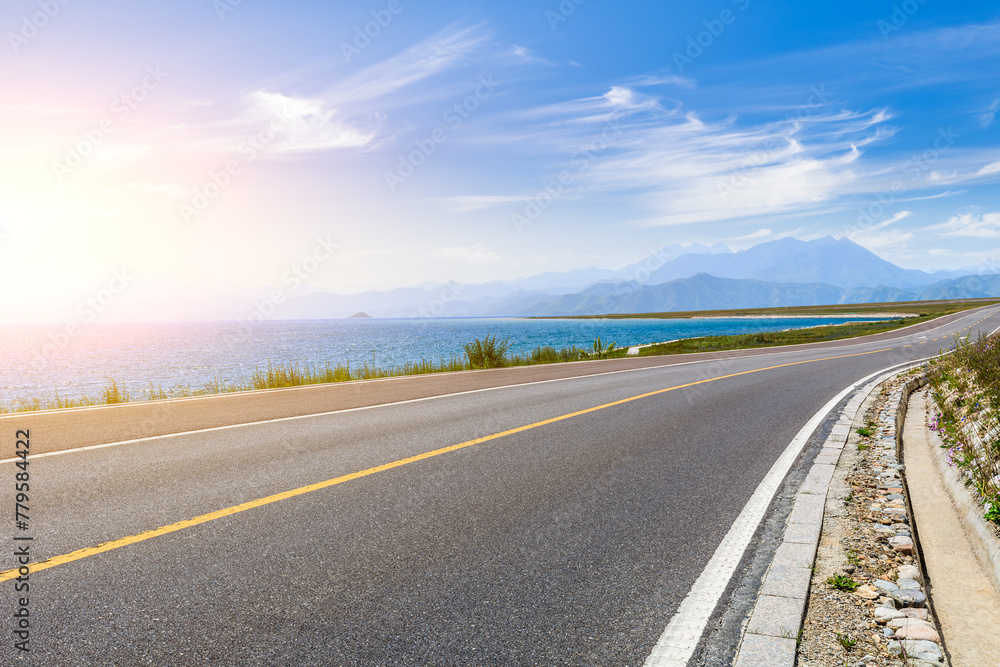 Fototapeta premium Asphalt highway and blue lake with mountain natural landscape
