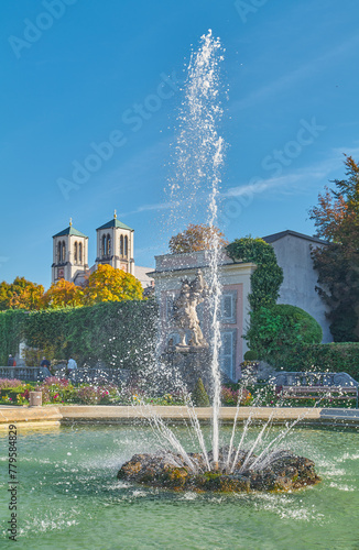 Salzburg, Austria -  October 6, 2022: The  fountain and garden of the Mirabell palac with the St Andrew bell tower in the background