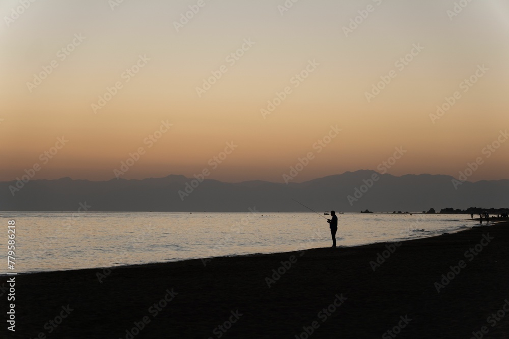 Silhouette of a fisherman on a seashore at sunset in Turkey