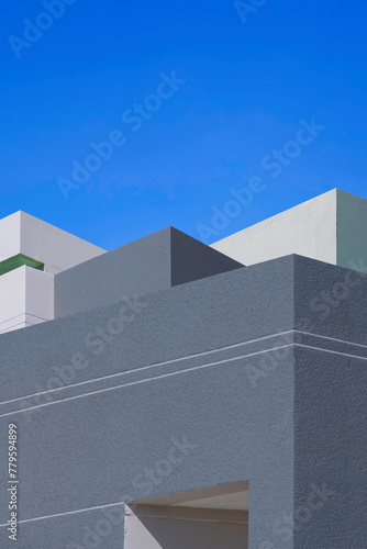 Modern geometric gray and white office buildings group against blue clear sky background in vertical frame, Exterior architecture in minimal style