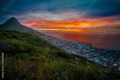 Gorgeous view of a mountainside town in Africa overlooking the calm sea at sunset © Wirestock