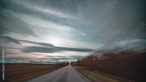 Fast drive forward timelapse through the windswept autumn tundra. Dark clouds whirl above the road. photo