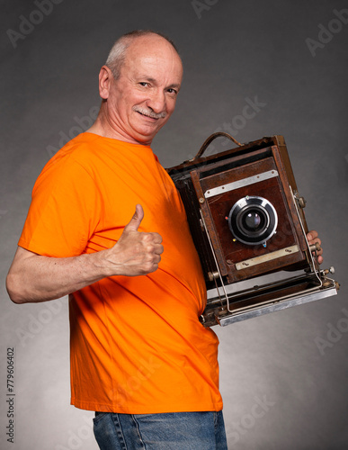 Obraz na płótnie Senior man holding retro photocamera in studio w salonie