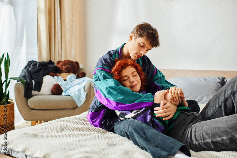 Obraz premium good looking jolly man in vivid attire hugging his pretty joyous girlfriend in bed at home
