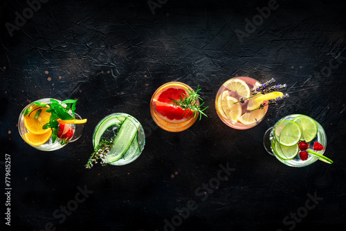 Fancy cocktails with fresh fruit. Gin and tonic drinks with ice at a party, on a black background, overhead flat lay shot