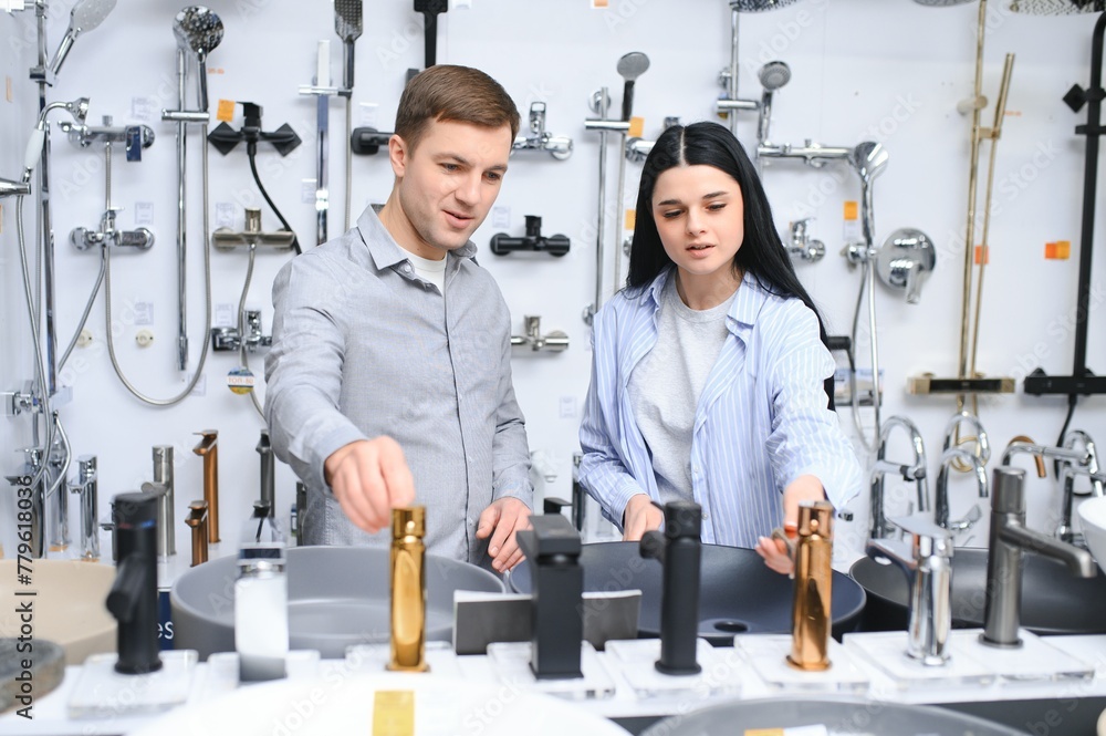 Couple choosing new sink faucet for their home in modern appliances store Couple choosing new sink faucet for their home in modern appliances store