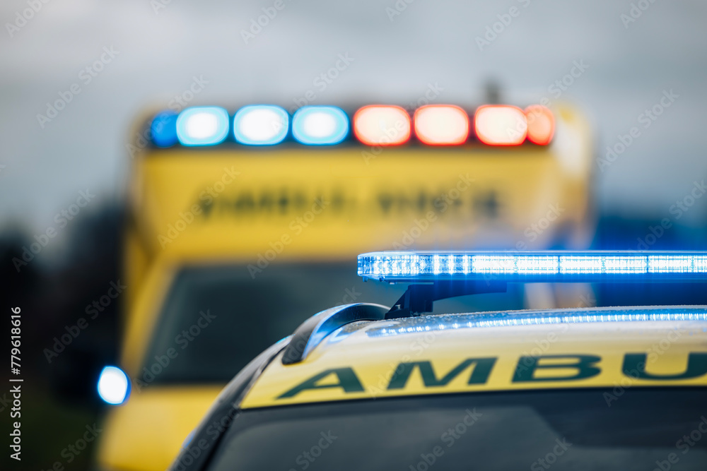 Close-up of blue light flasher on roof of ambulance car of emergency medical service on road. Themes rescue, urgency and health care... - obrazy, fototapety, plakaty 