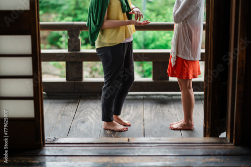Two friends casually chat by a wooden railing, the lush backdrop hinting at a tranquil, natural setting photo